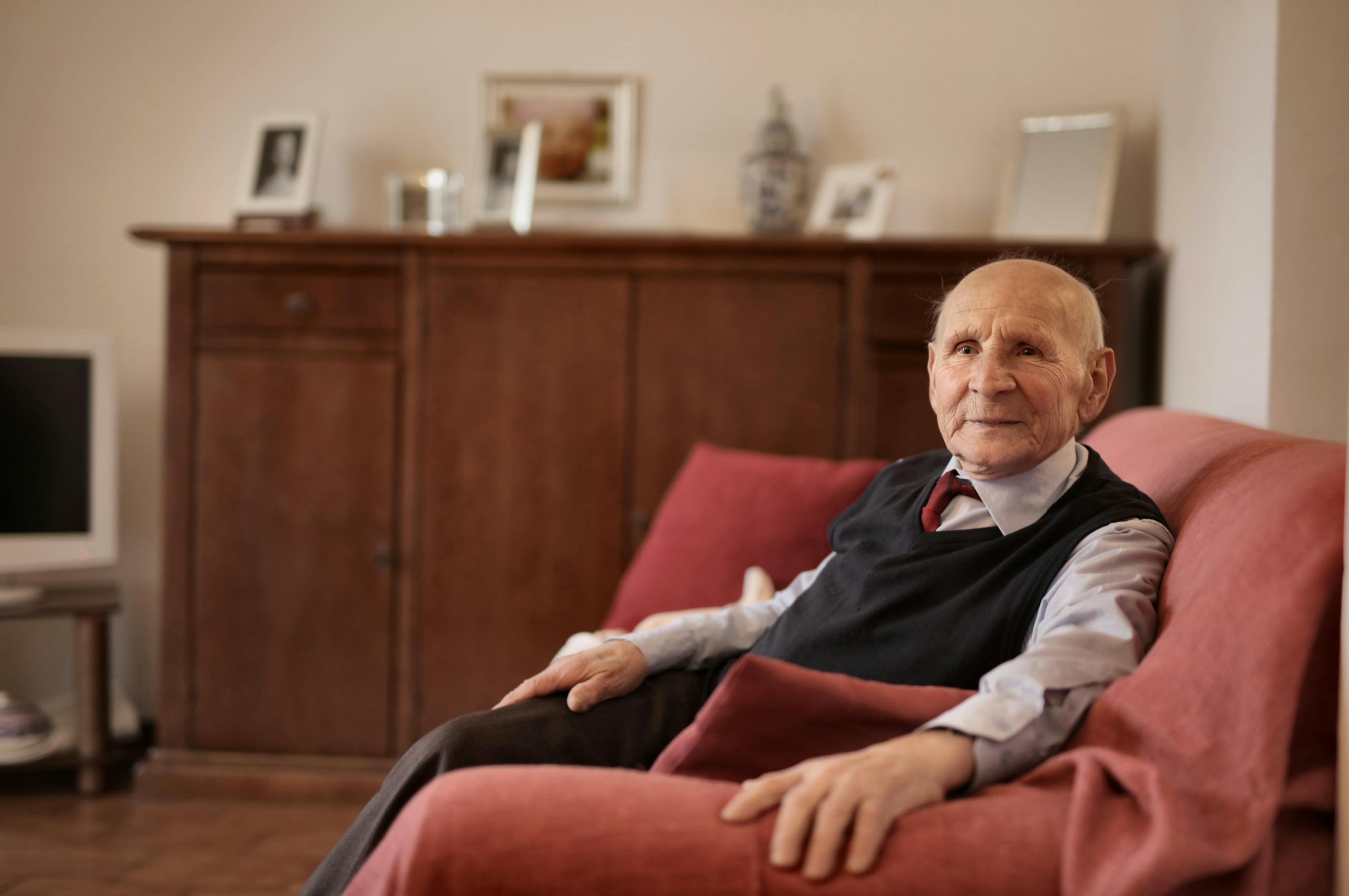 Senior man sitting comfortably on a sofa in a warm and inviting living room.