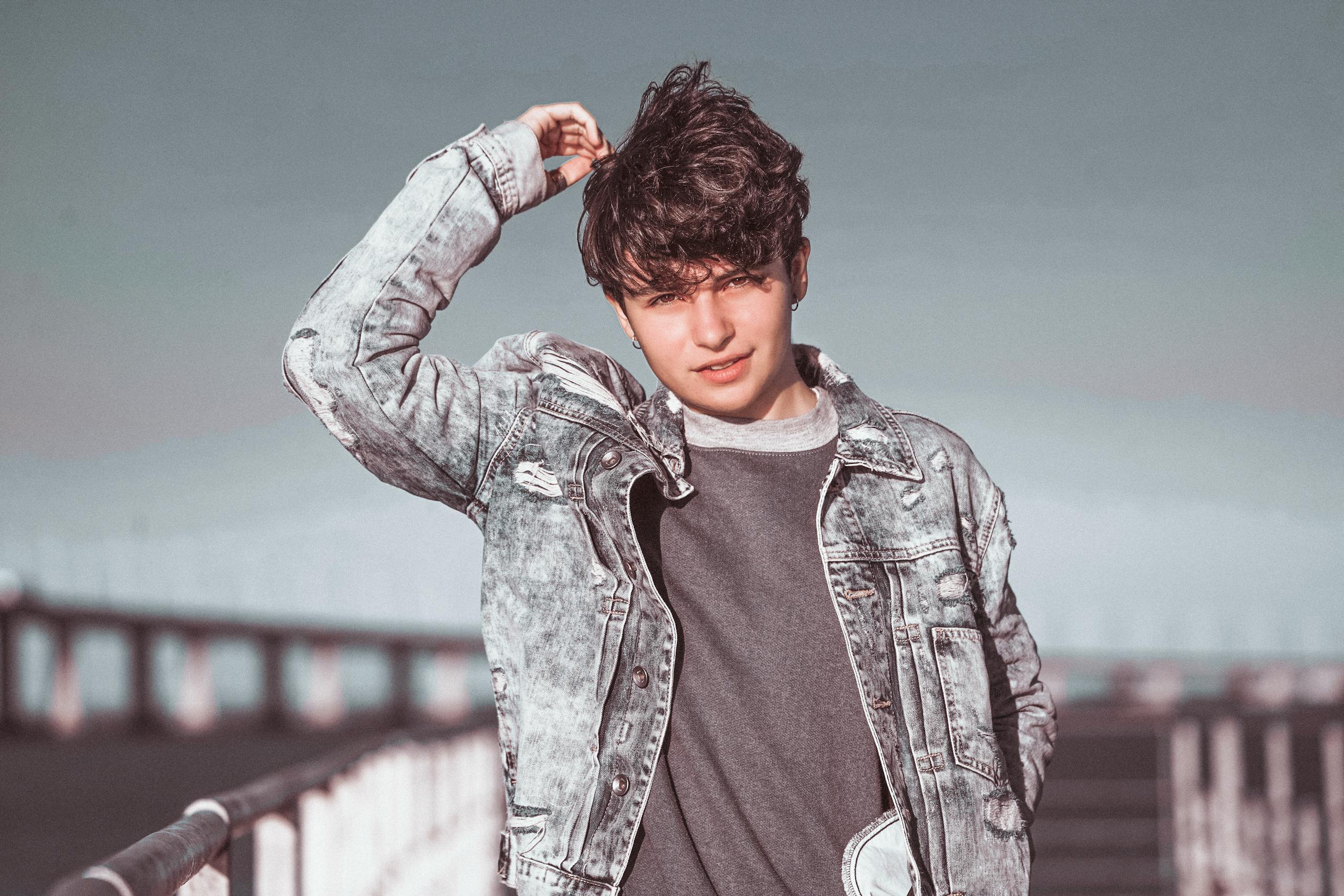 Teenager wearing a denim jacket outside on a bridge. Perfect for lifestyle themes.