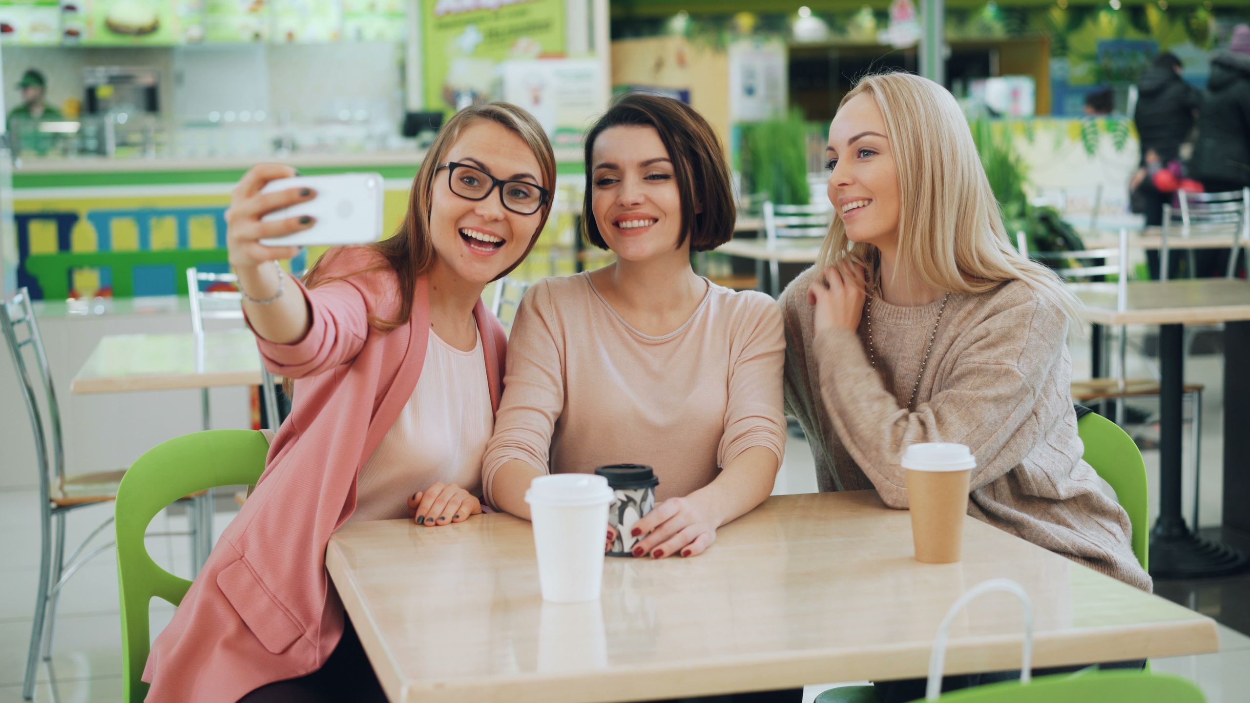 Three friends capturing a joyful moment with a selfie in a trendy cafe.