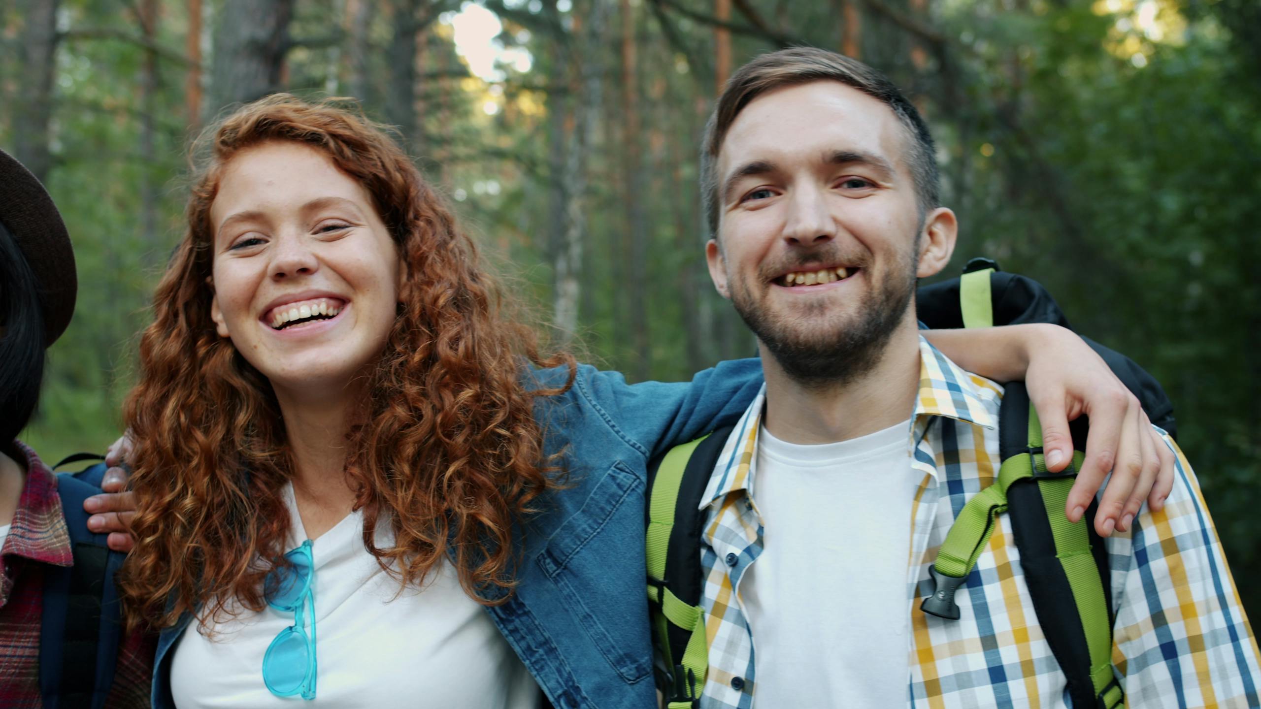 Two friends smiling during a forest hike, enjoying nature and friendship.