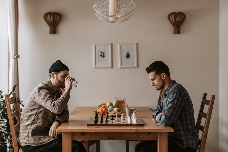 Two men playing chess indoors with focused expressions, highlighting strategic thinking.
