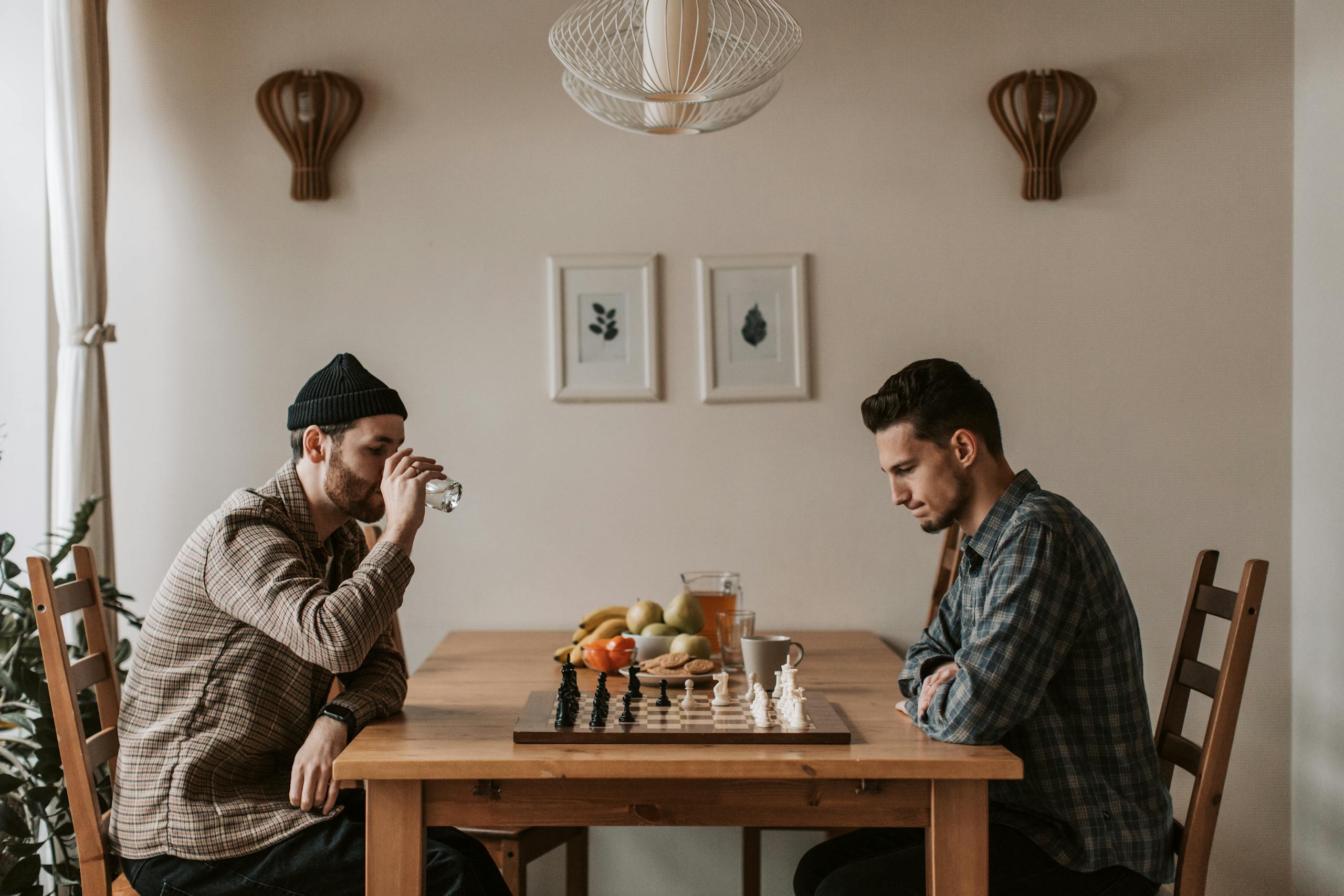 Two men playing chess indoors with focused expressions, highlighting strategic thinking.
