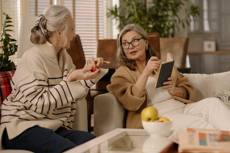 Two senior women having a warm and intimate conversation on a cozy couch indoors.