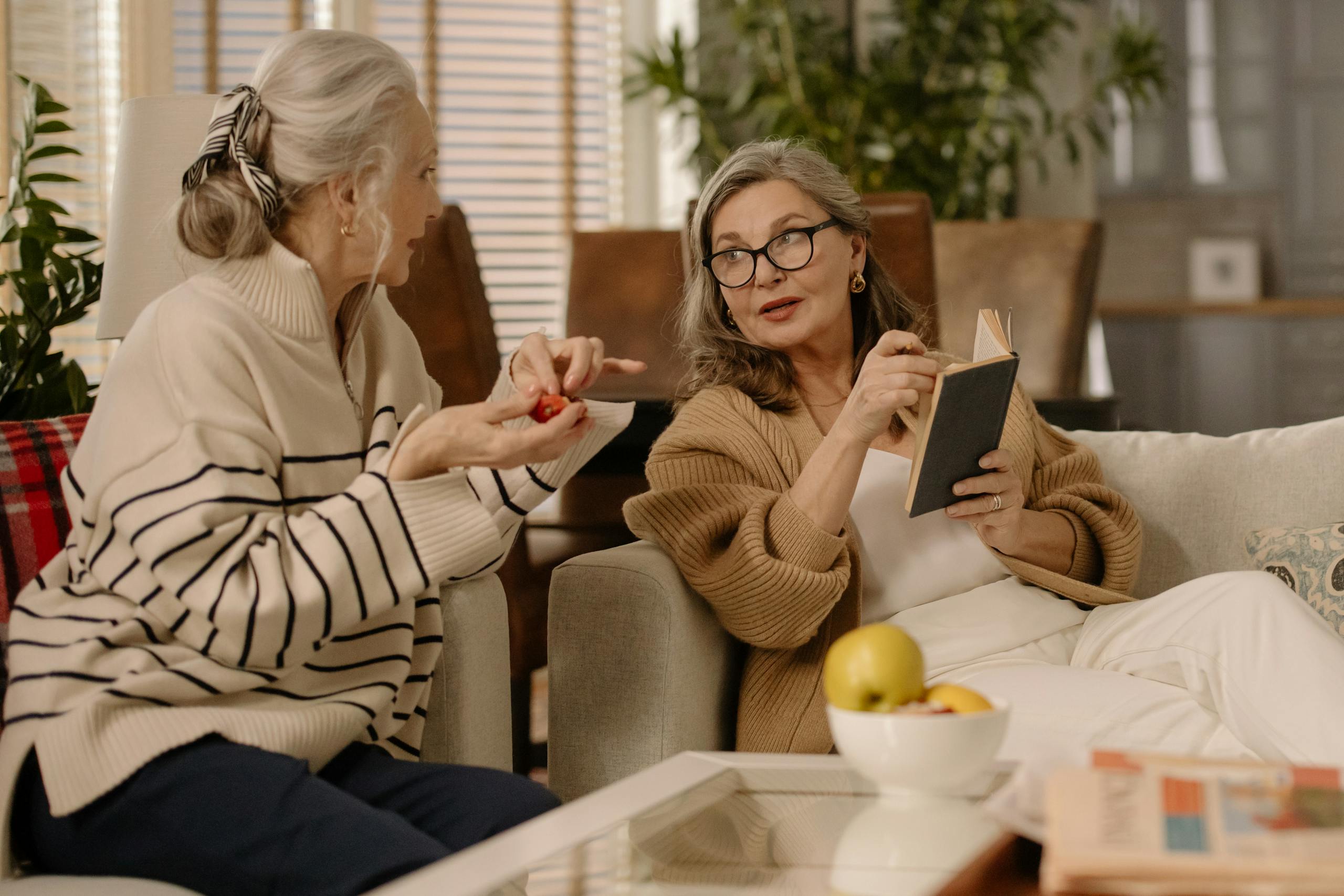 Two senior women having a warm and intimate conversation on a cozy couch indoors.