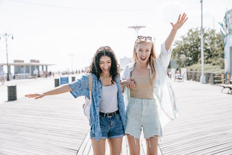 Two women having fun on a sunny boardwalk, embracing friendship and summer vibes.