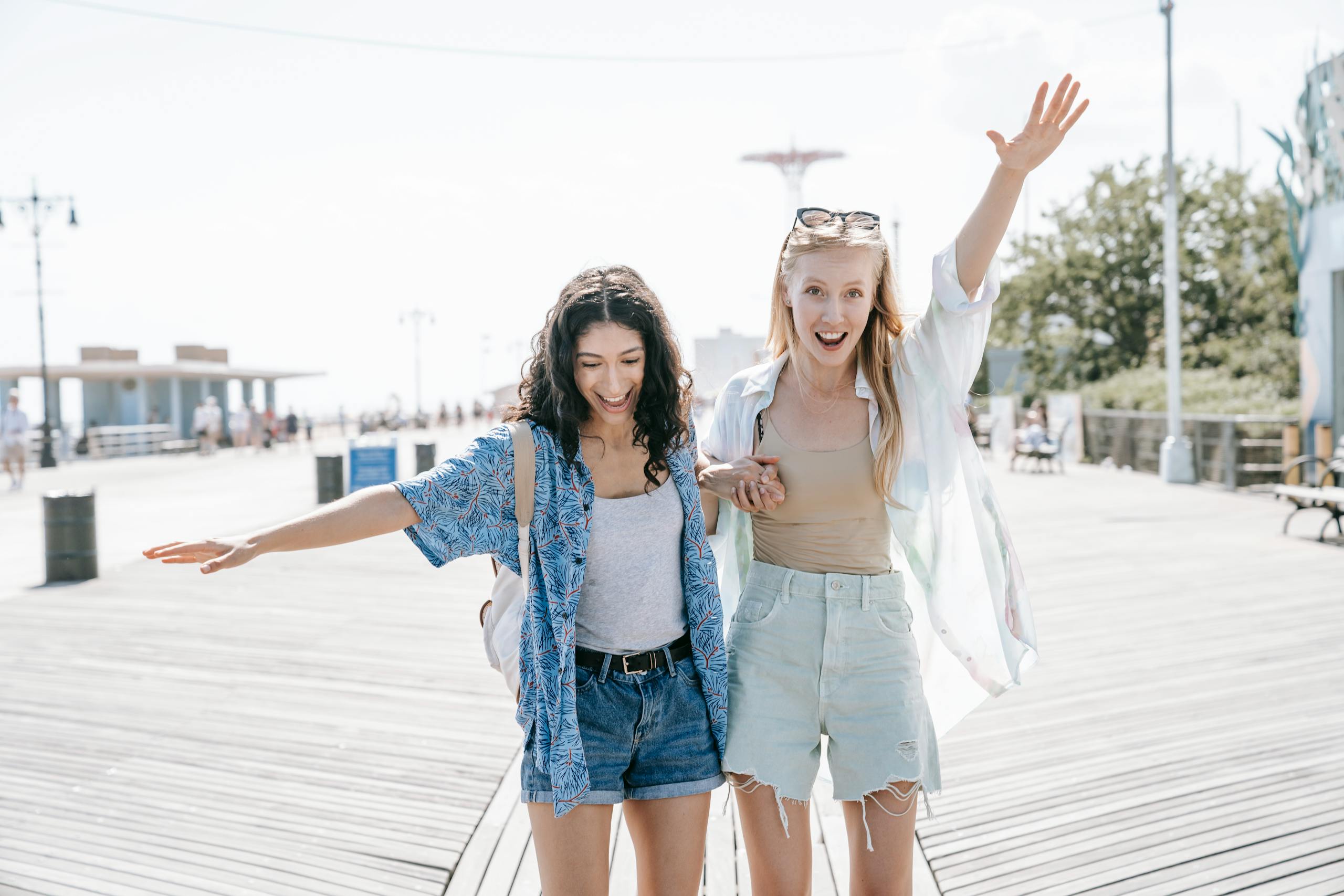 Two women having fun on a sunny boardwalk, embracing friendship and summer vibes.