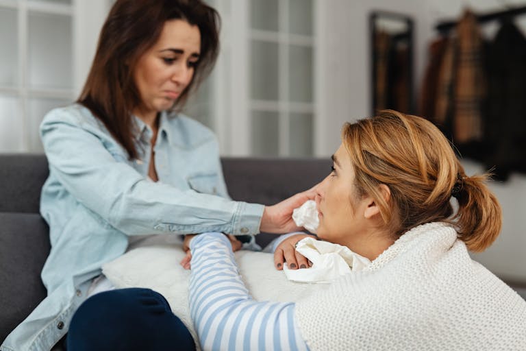 Two women share a moment of comfort and support indoors, expressing emotions.