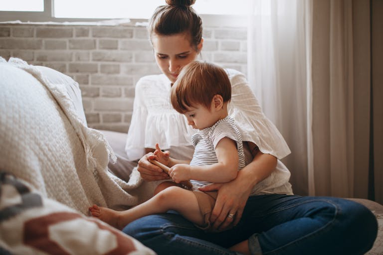 Warm indoor scene of a mother and toddler bonding on a cozy sofa, capturing a tender family moment.
