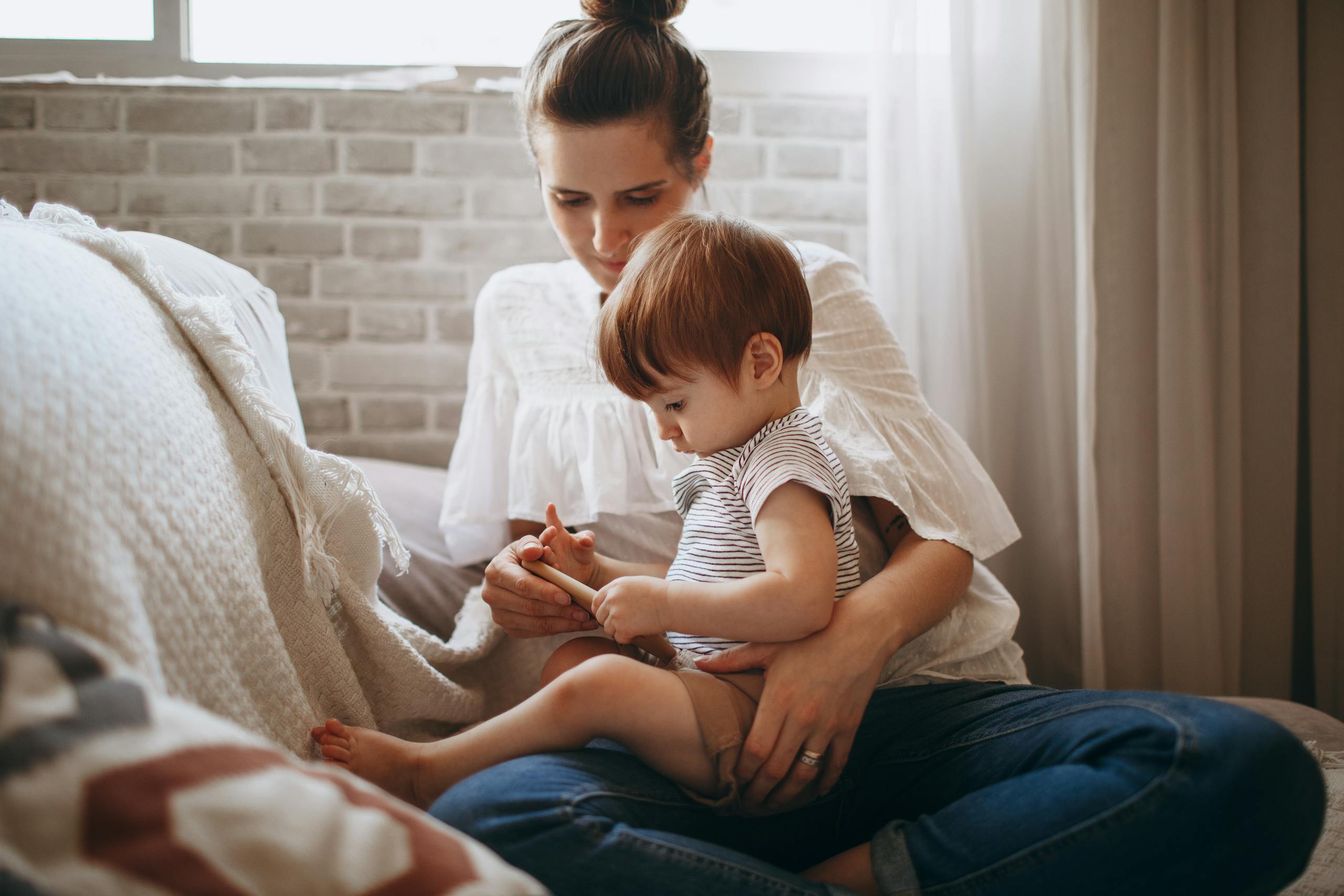 Warm indoor scene of a mother and toddler bonding on a cozy sofa, capturing a tender family moment.