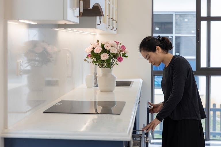 Woman in a modern kitchen beside roses, showcasing contemporary design.