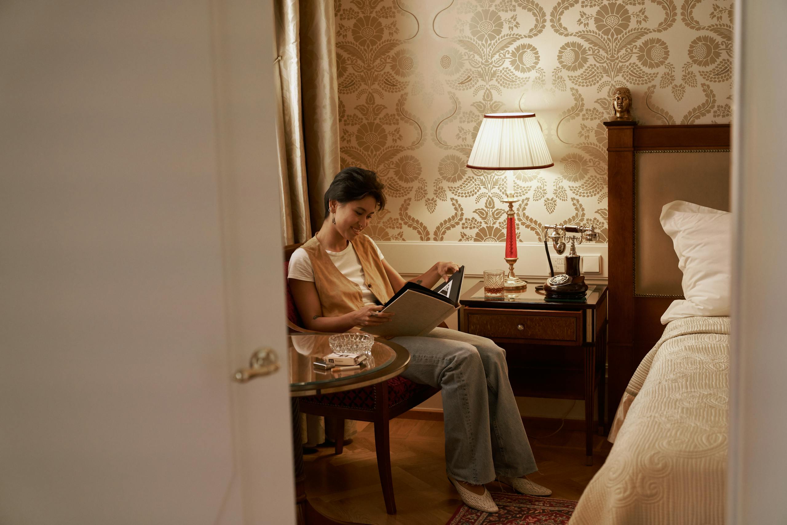 Woman reading in a cozy vintage bedroom with elegant decor.