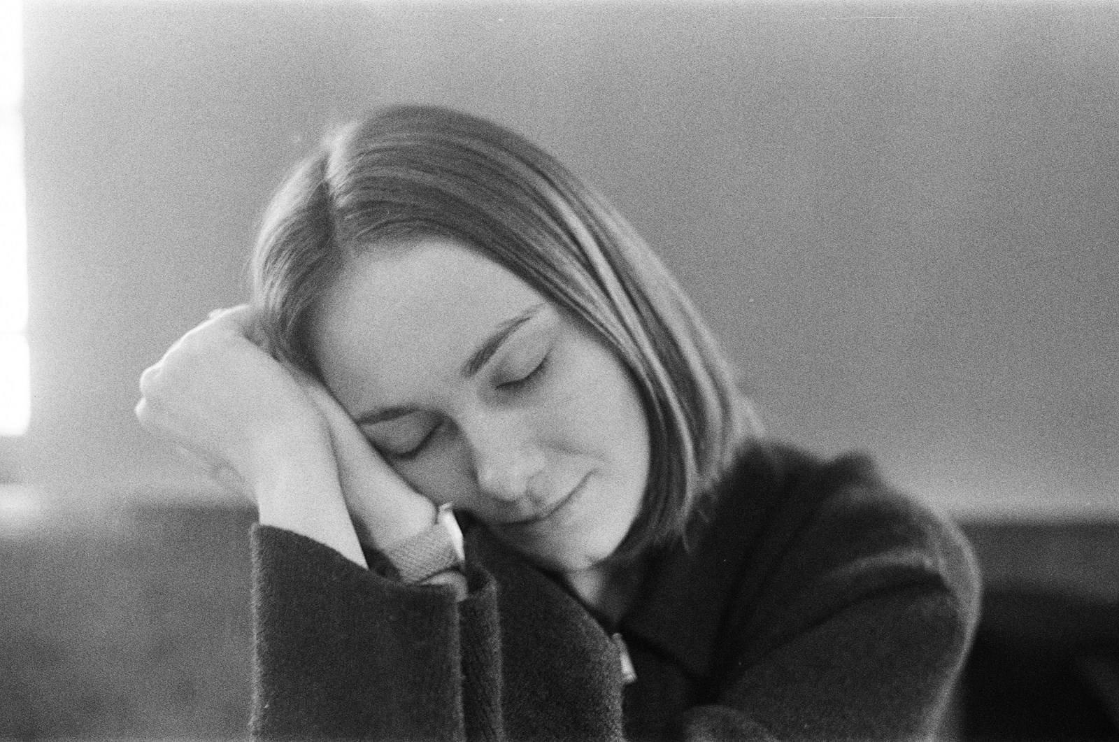 A young woman with eyes closed resting her head