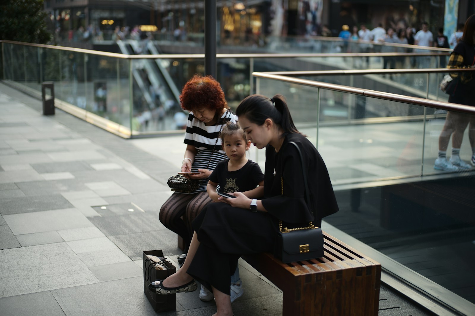 Woman and child looking at phone on a bench.