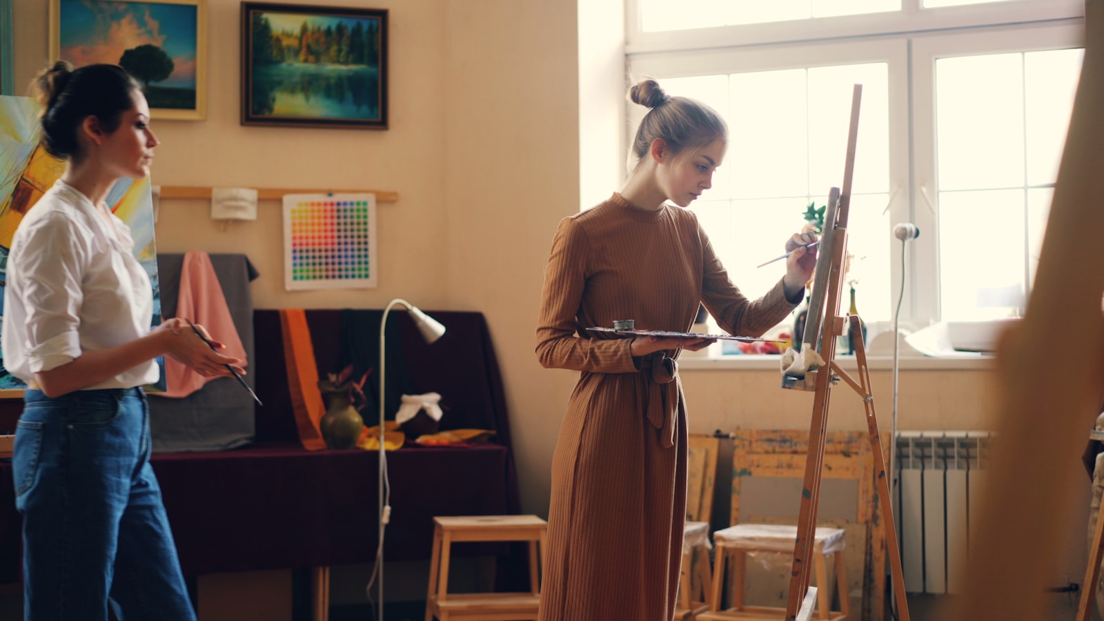 Two women are painting in an art studio.