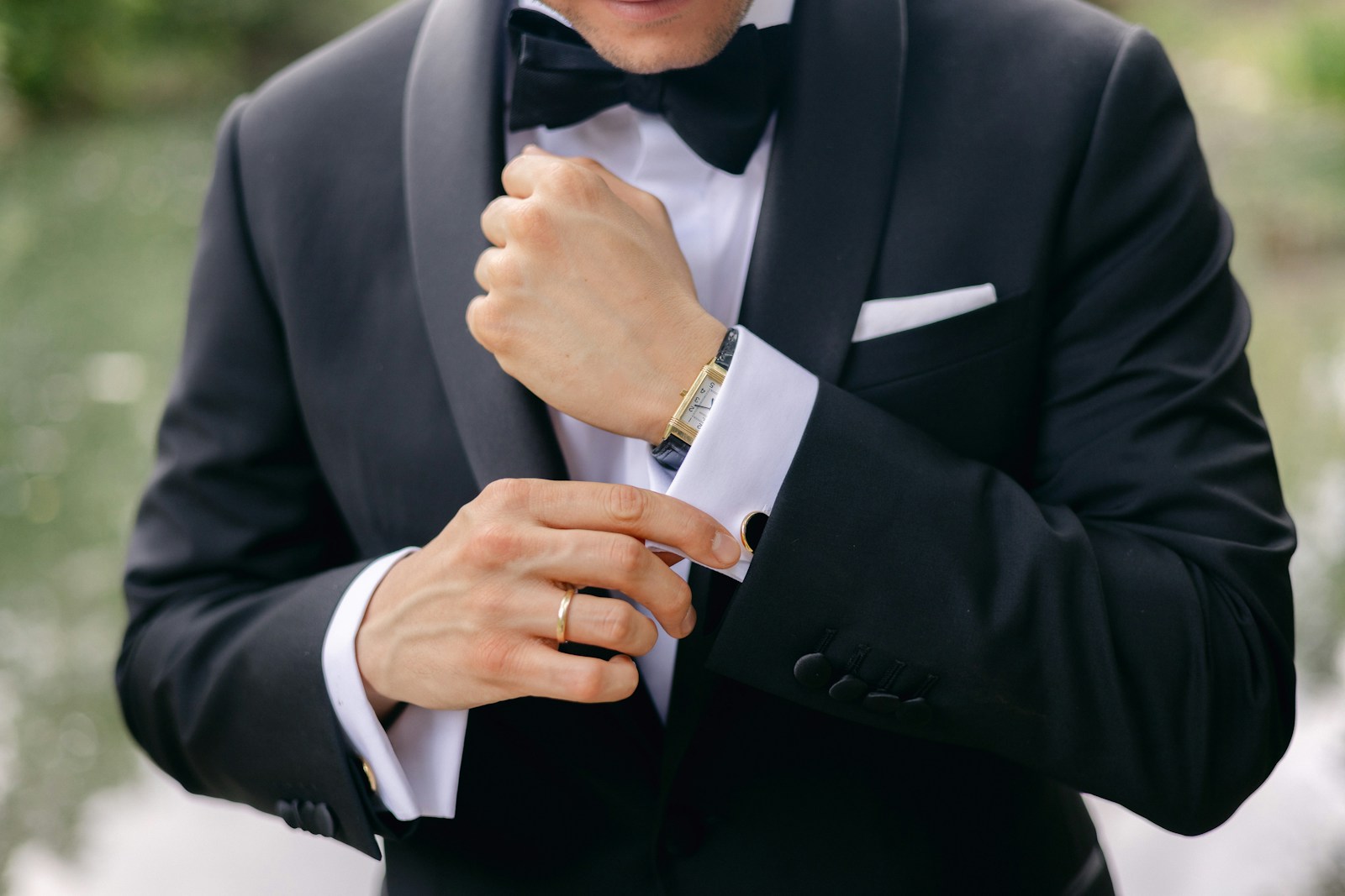 a man in a tuxedo adjusts his watch