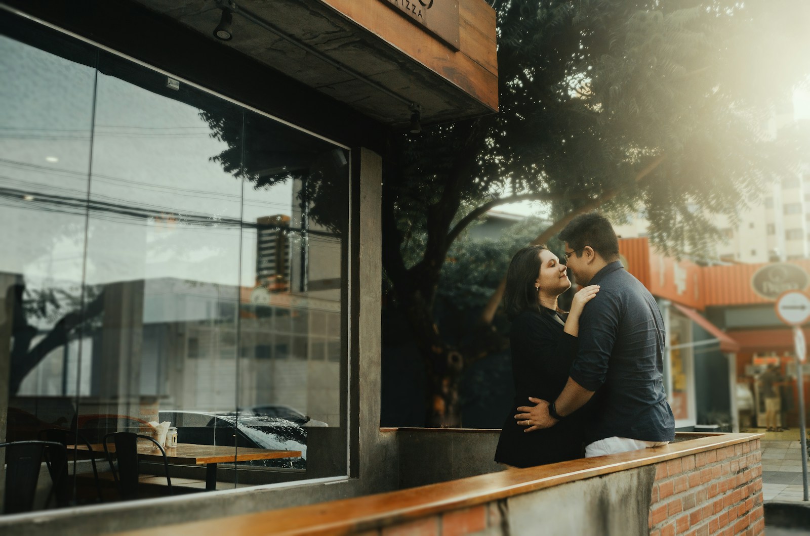 a man and a woman kissing in front of a window