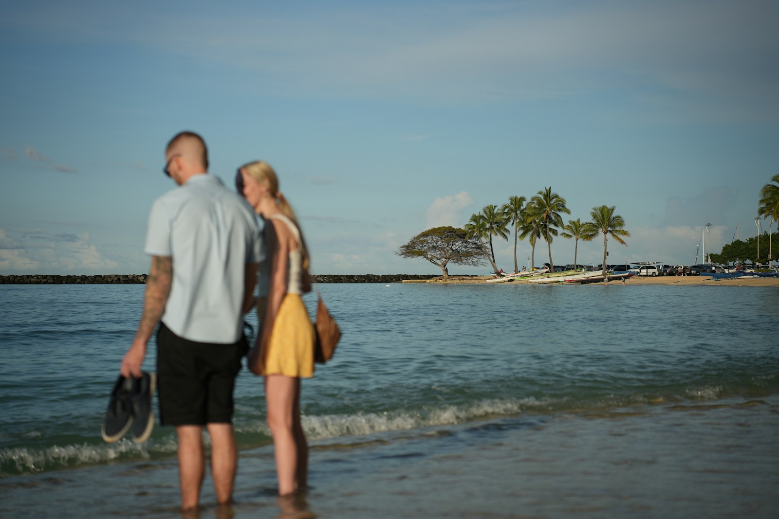 Couple standing in shallow ocean water with palm trees.