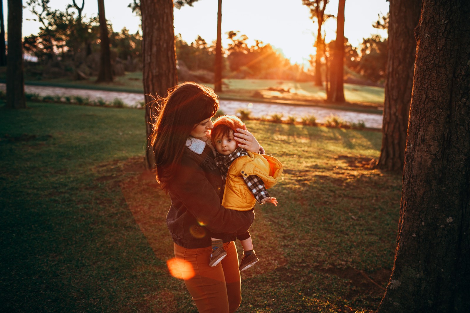 girl in black jacket and blue denim jeans running on green grass field during daytime