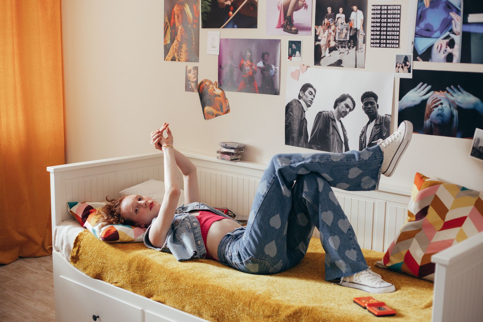 Teenager lying on a bed in a cozy, poster-filled room, enjoying a moment of relaxation.