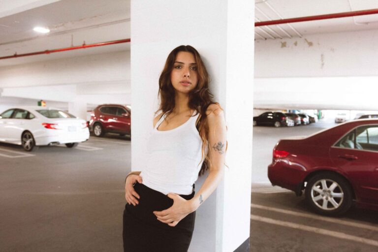 Chic woman in casual fashion posing against pillar in a parking garage. Urban style and confidence.