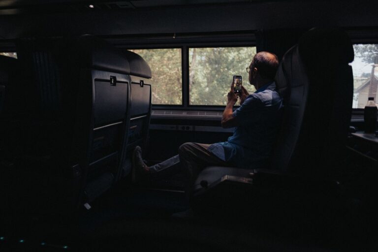 Senior man captures scenic views from a train window using a smartphone.