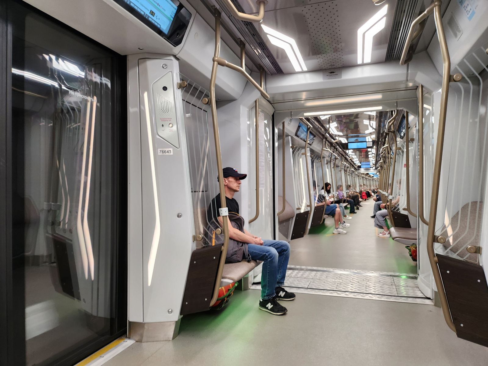 Interior view of a modern subway train with people seated, showcasing urban transit.