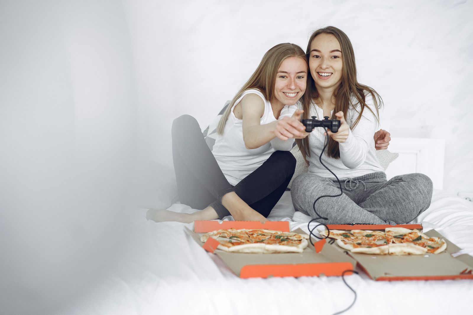 Two women enjoying a fun gaming session at home, bonding over pizza and leisure activities.