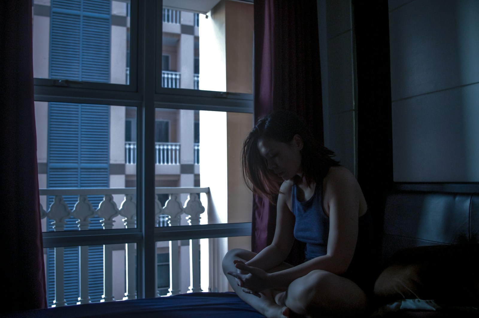 a girl sitting on a bed looking at her cell phone