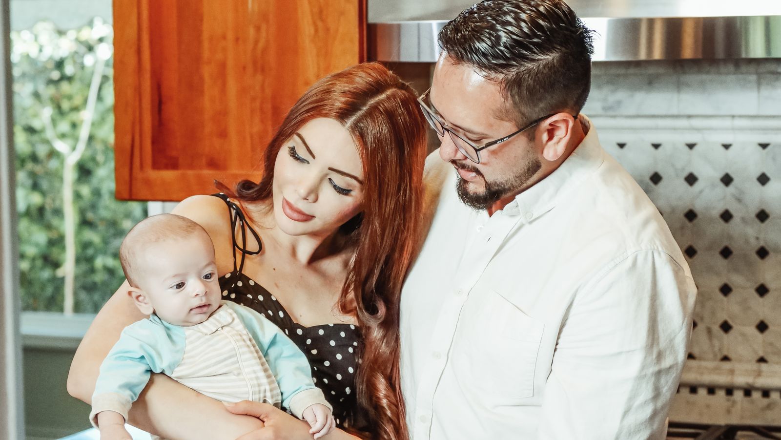 A joyful family moment with parents and baby in a modern kitchen environment.