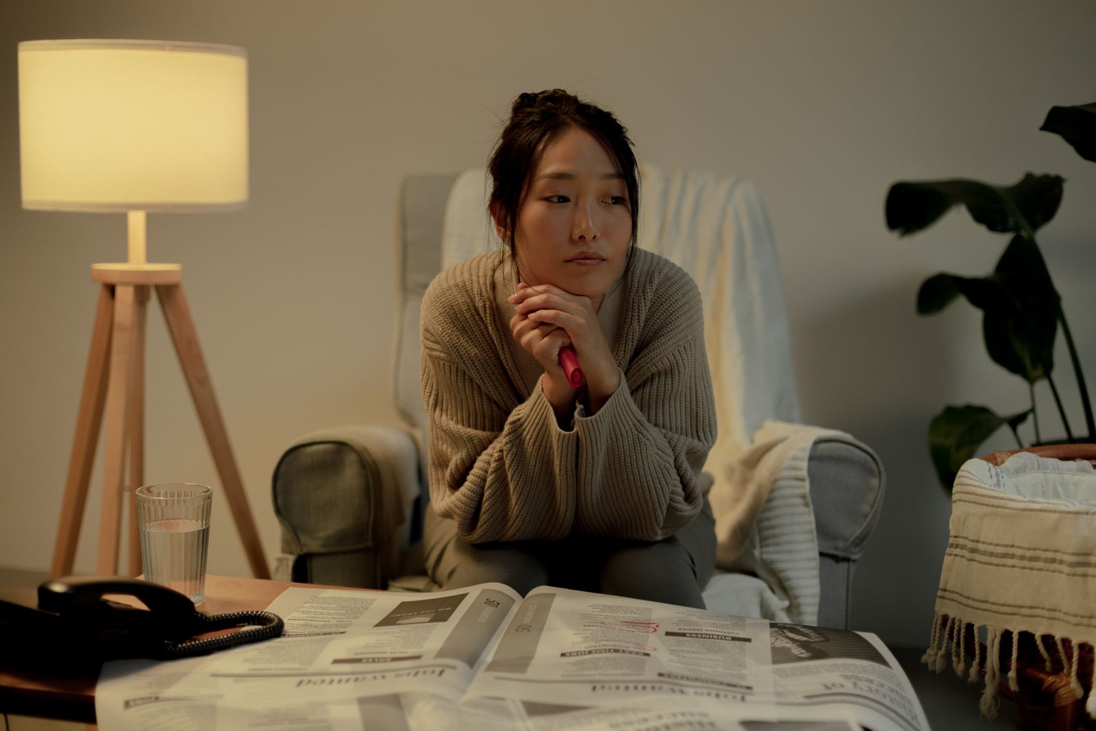 A woman in an armchair, contemplating job search in a cozy living room.