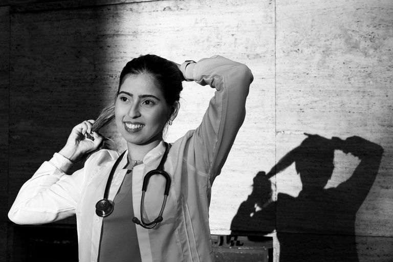 A black and white portrait of a smiling female doctor in Buenos Aires, with her shadow on the wall.