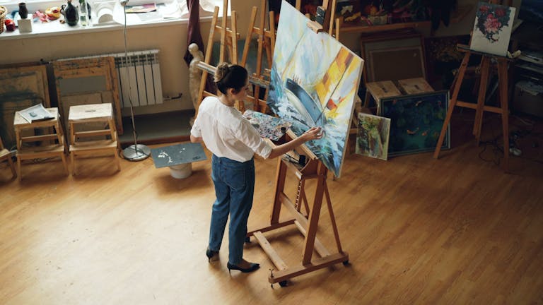 A female artist working on a seascape painting in her art studio.