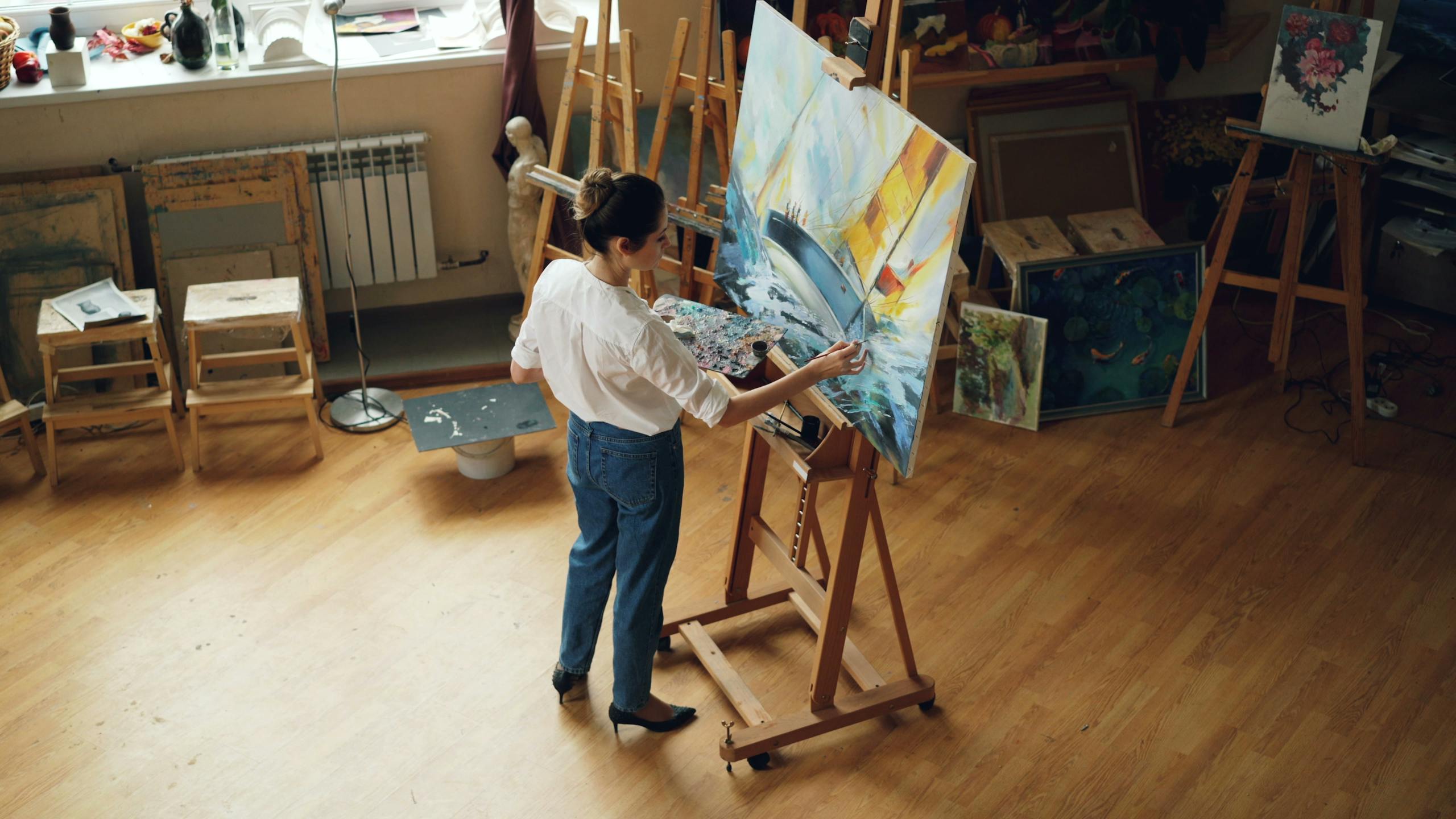 A female artist working on a seascape painting in her art studio.