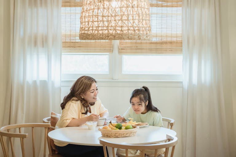 A heartwarming scene of a mother and daughter sharing breakfast in a cozy home setting.