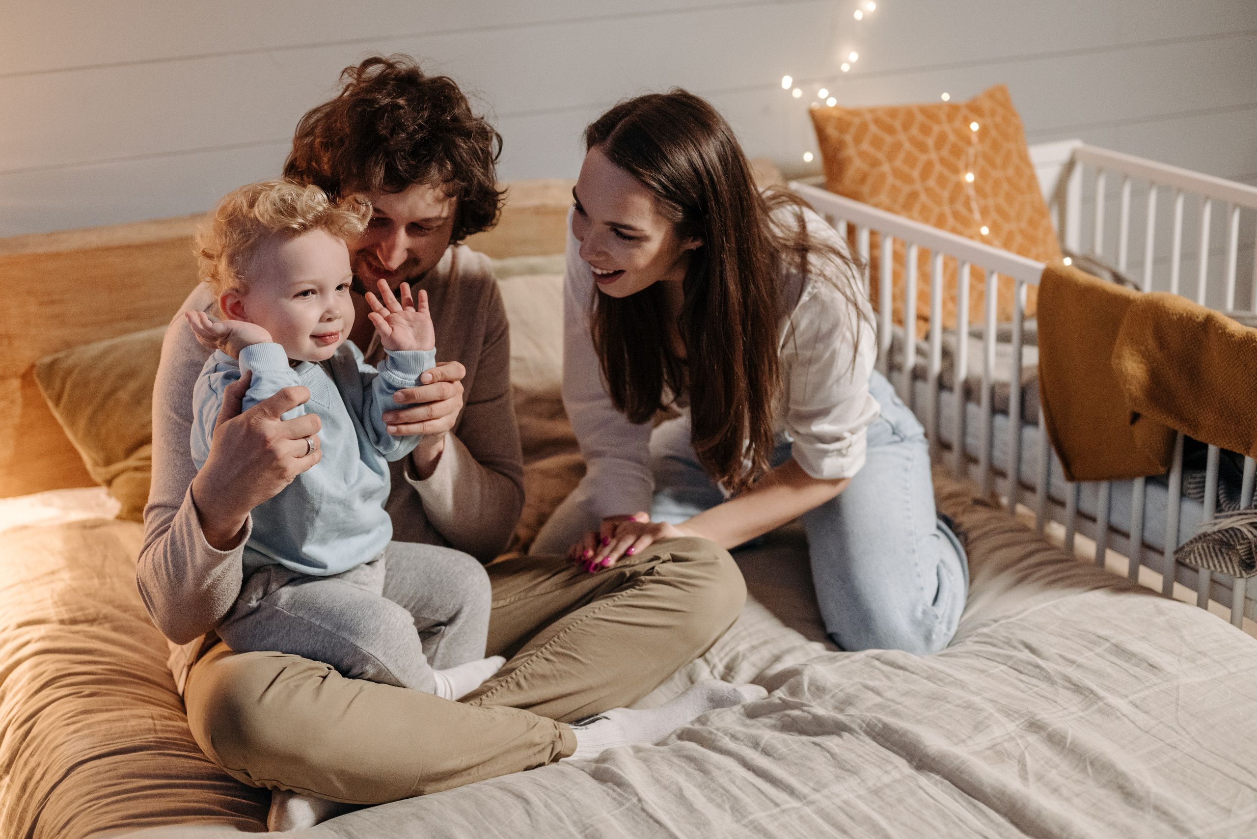A joyful family moment with parents and child in a cozy bedroom, filled with warmth and laughter.