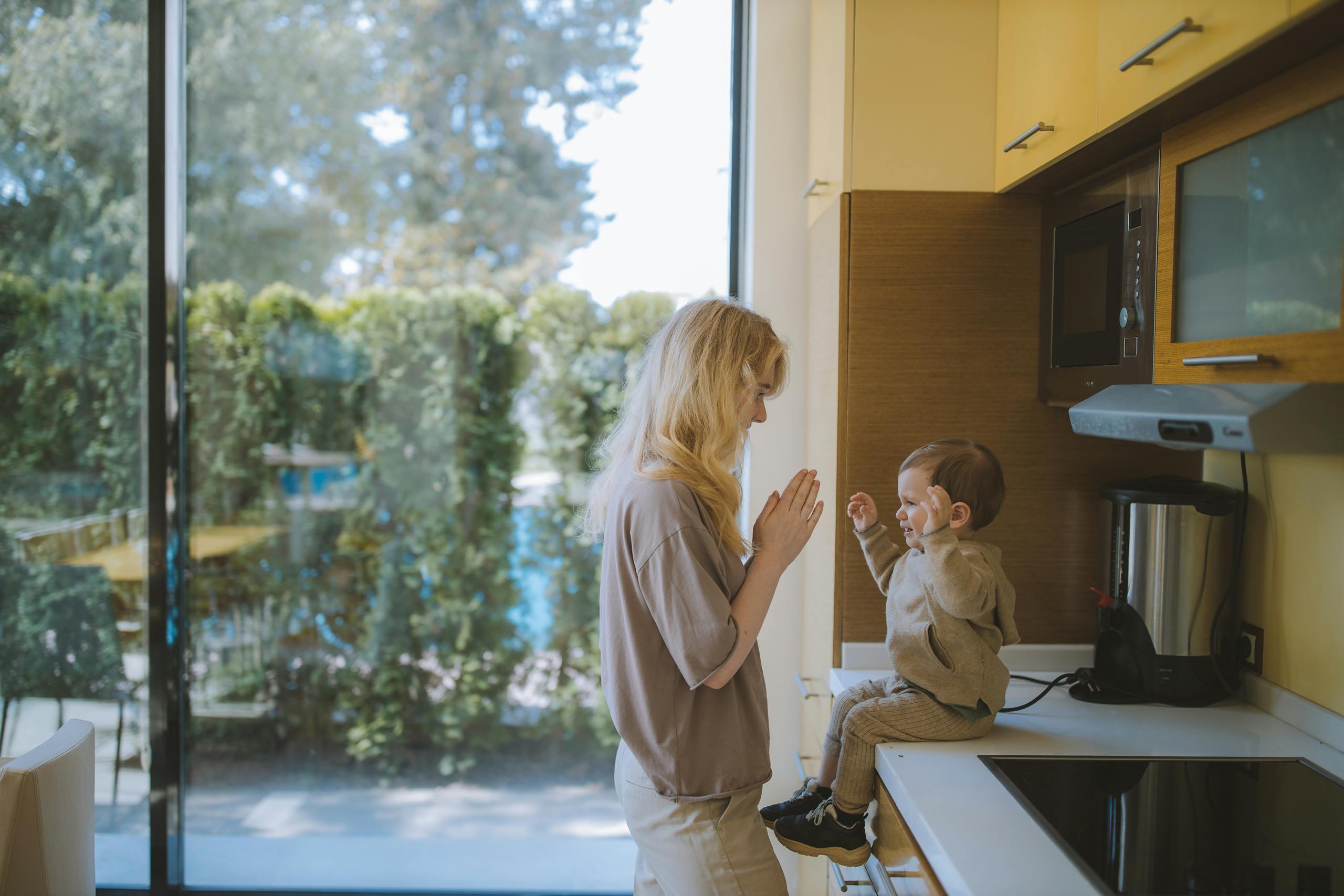 A joyful moment of a mother and child playing together in a bright kitchen.