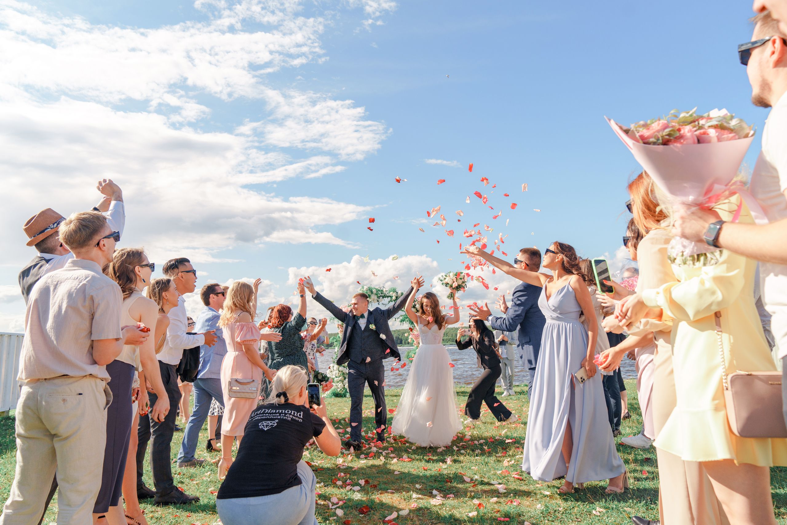 A joyful outdoor wedding celebration with a bride and groom surrounded by guests and confetti.