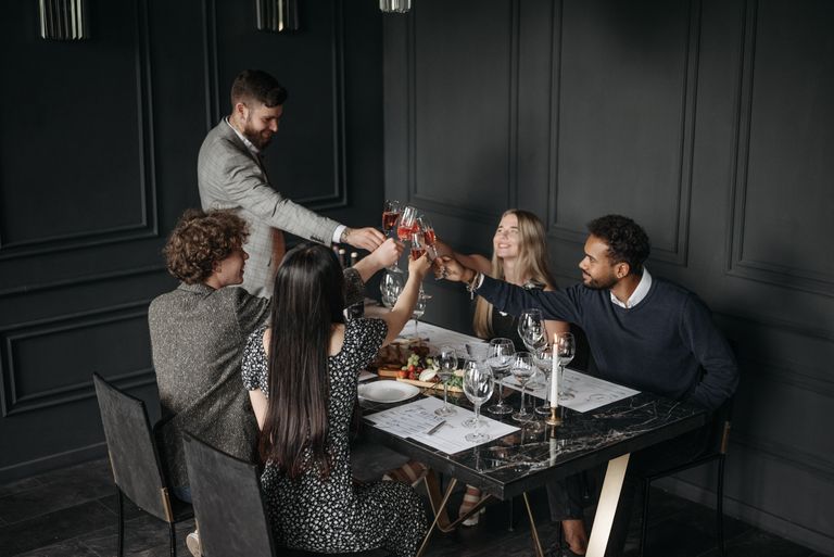 A sophisticated group enjoying a toast with wine at a stylish dinner setting, celebrating togetherness.