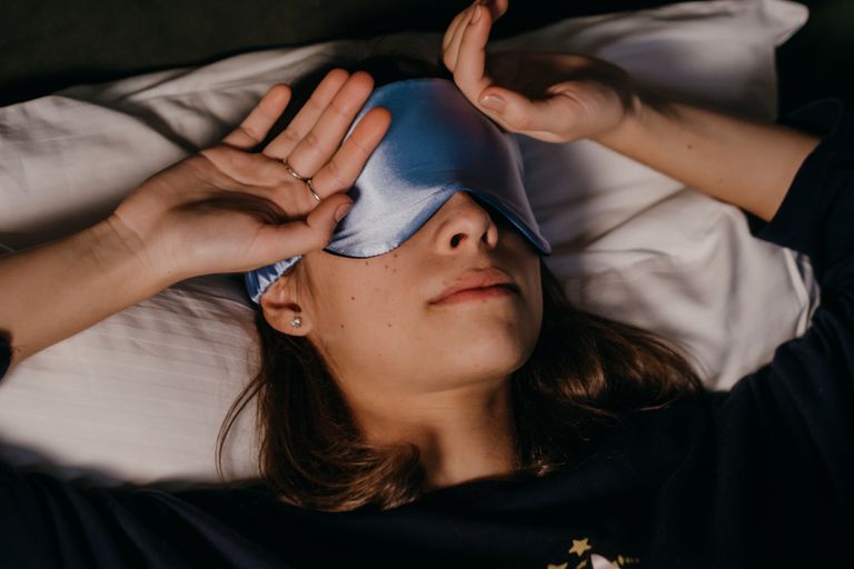 A woman peacefully resting with a sleep mask in a cozy indoor setting.