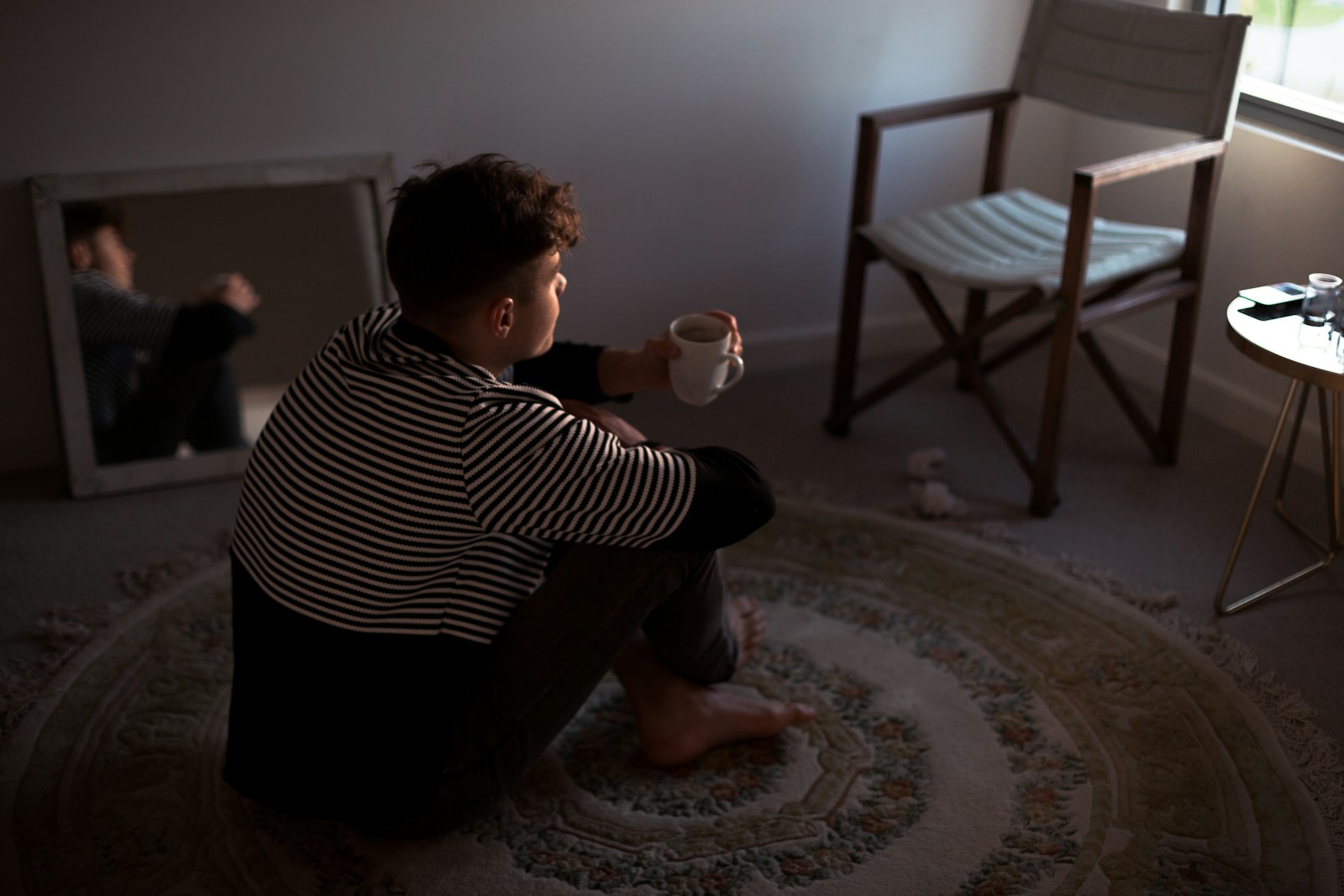 man sitting on rug in front of window