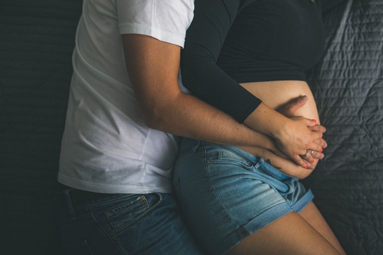 Close-up of a couple lovingly embracing a pregnant belly, symbolizing love and expectation.