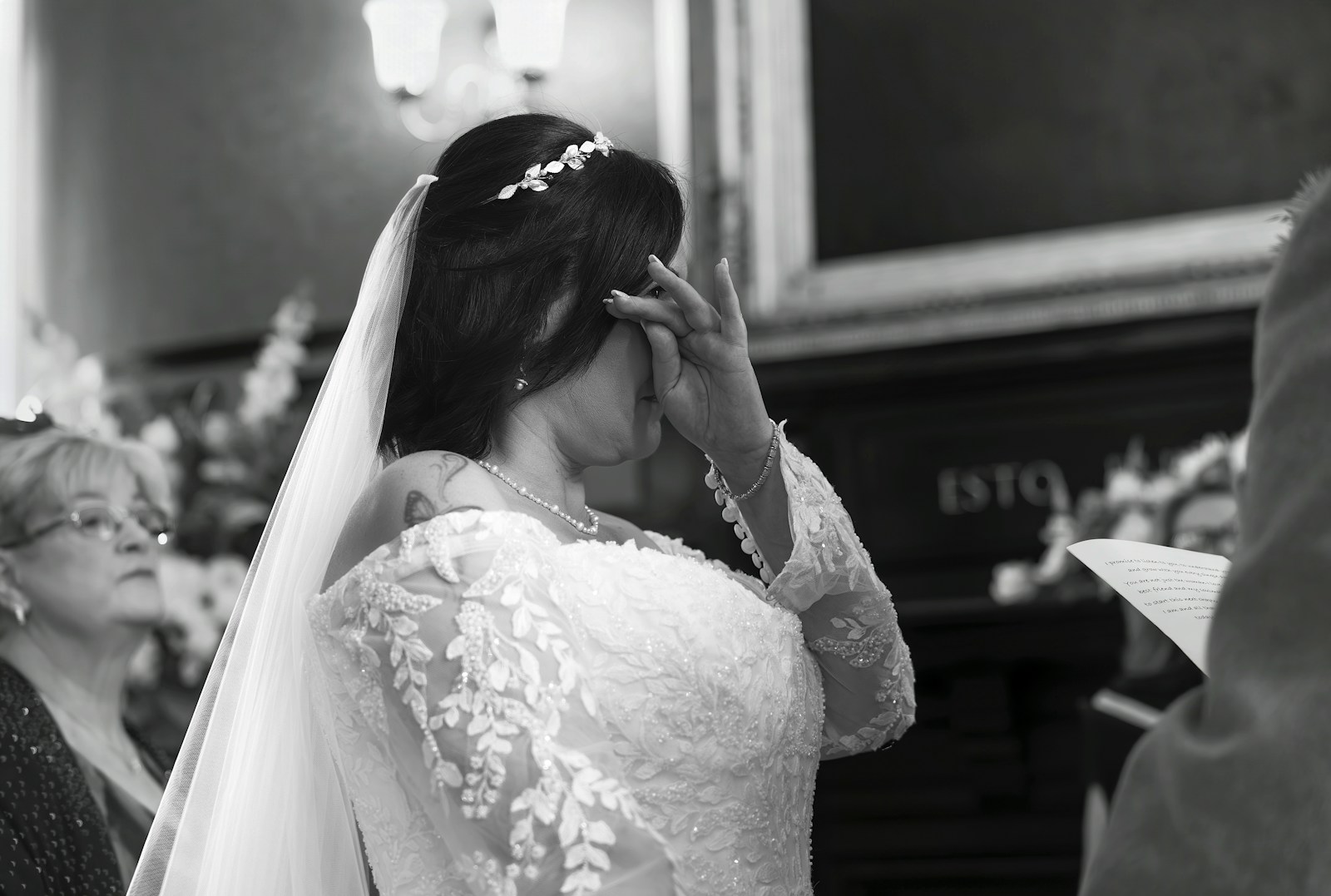 Bride in wedding dress wiping her eye during ceremony.