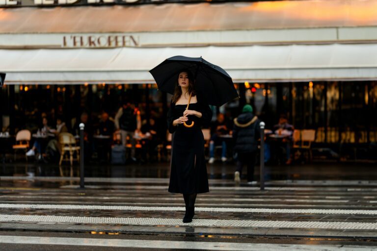 a woman walking across a street holding an umbrella