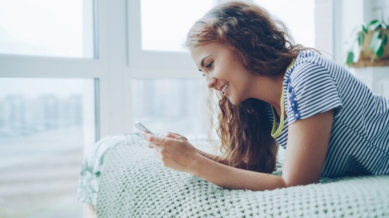 Young woman smiling while looking at her phone