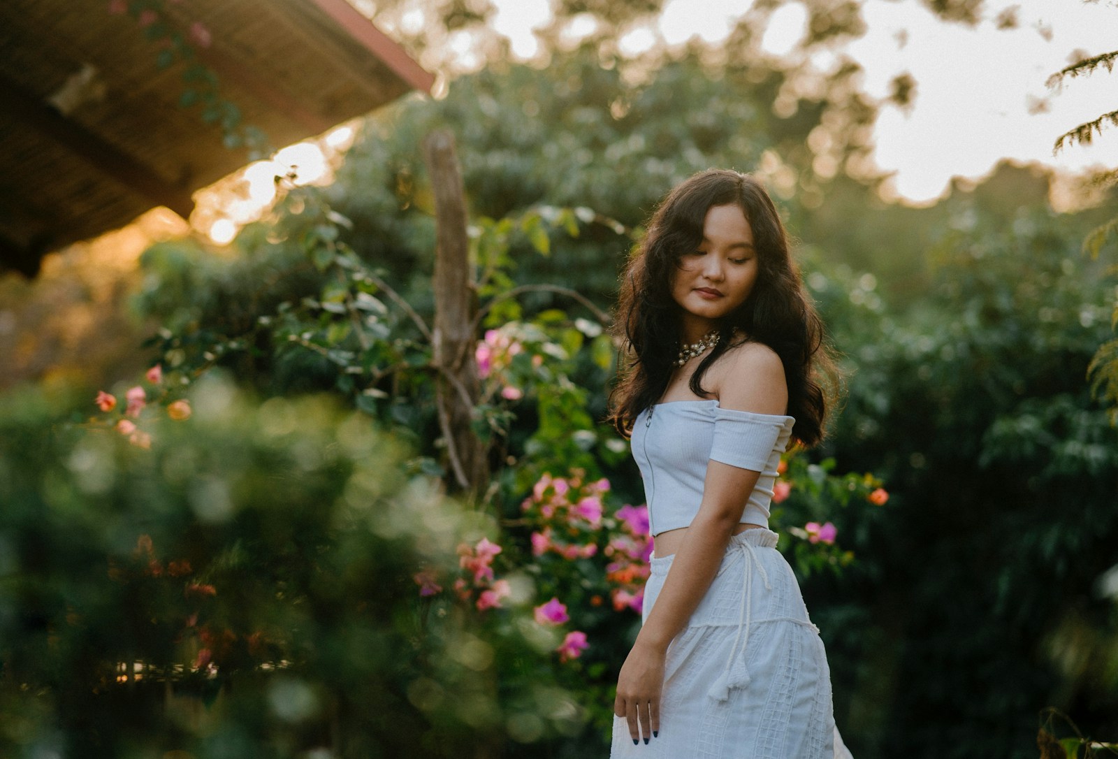 Young woman poses gracefully amongst beautiful greenery.
