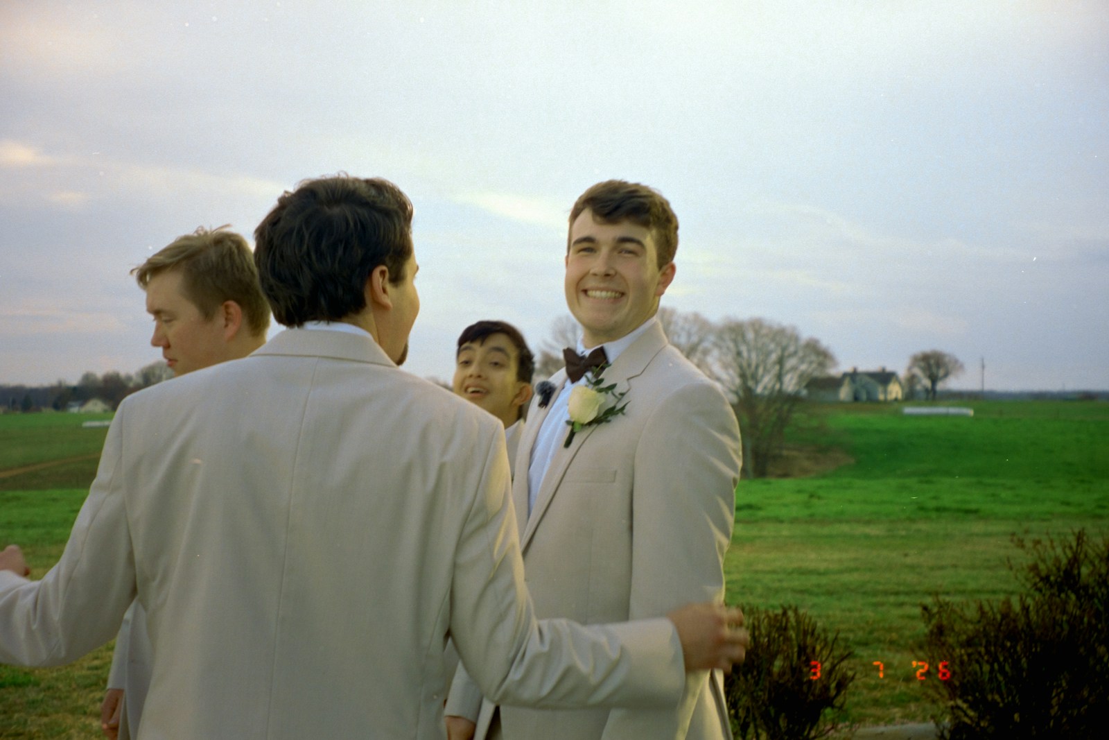 Groom smiling with groomsmen outdoors