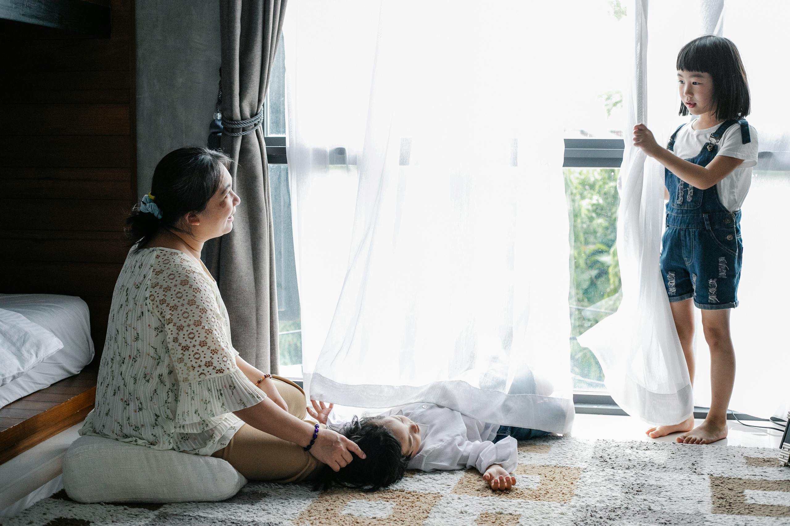 Full body of aged woman caressing grandson while communicating with little girl in cozy room