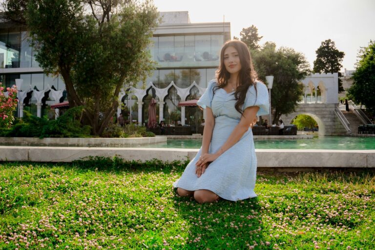Woman kneeling in grass with building background