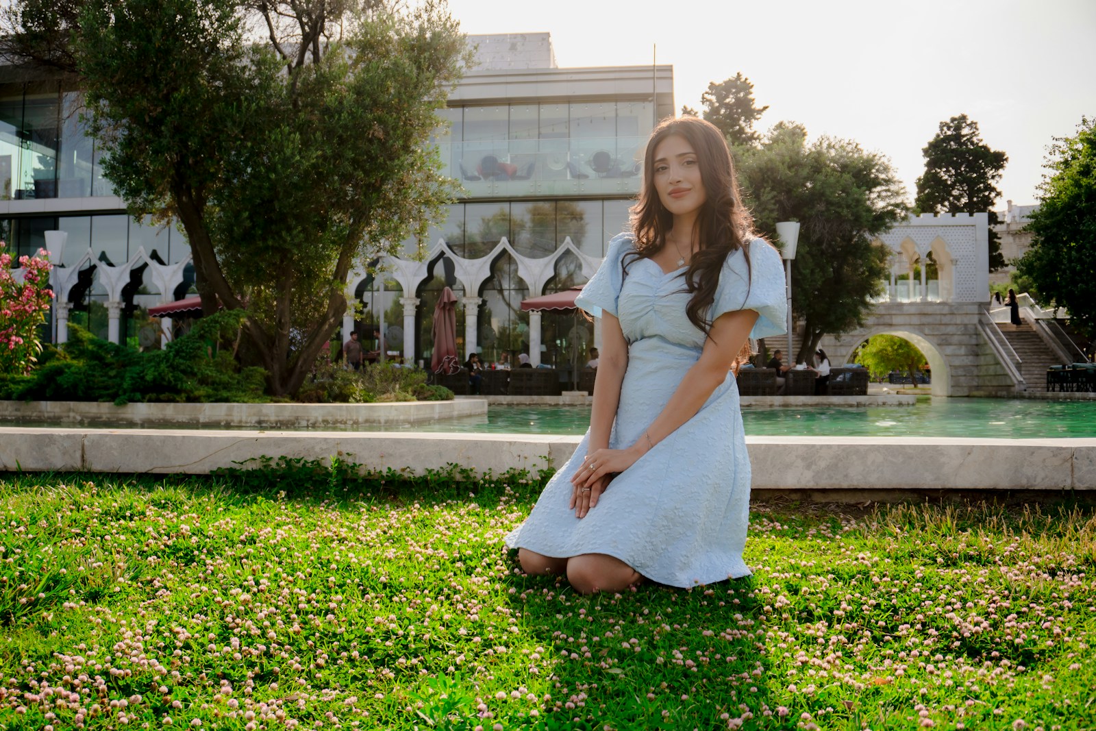 Woman kneeling in grass with building background