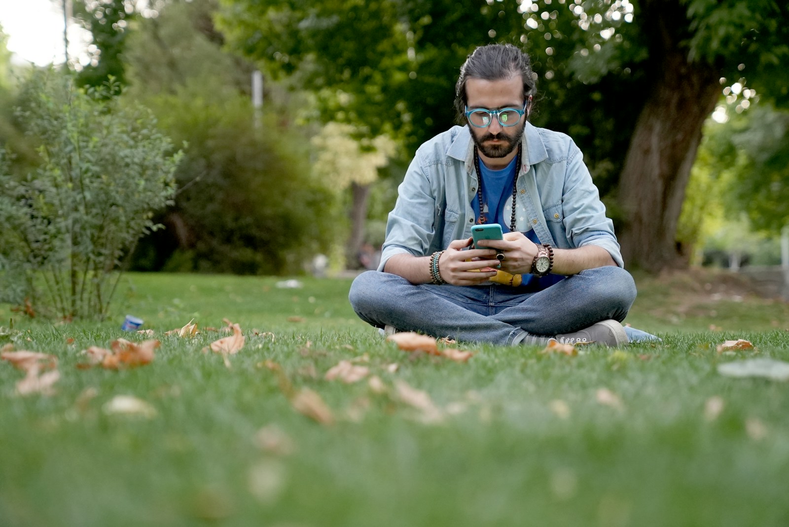 a man sitting in the grass looking at his cell phone